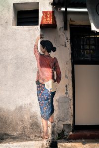 woman lighting incense sticks street art mural Penang